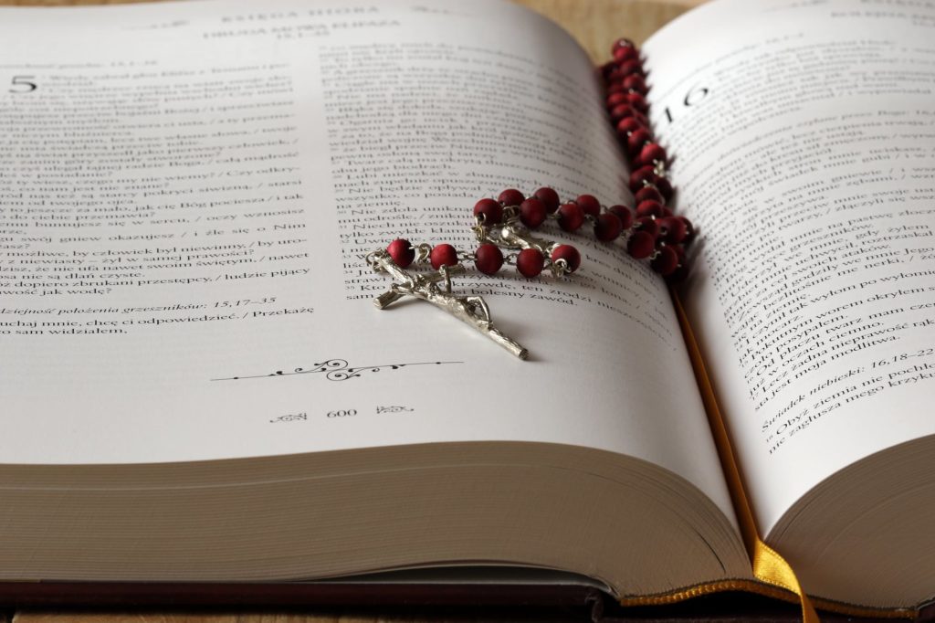 Rosary beads on a Bible Catholic church settlements Merson Law PLLC